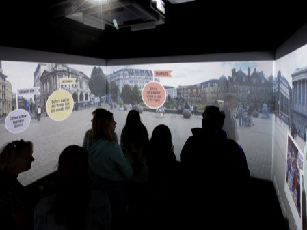 A group watch a video tour of Birmingham in a Cube system