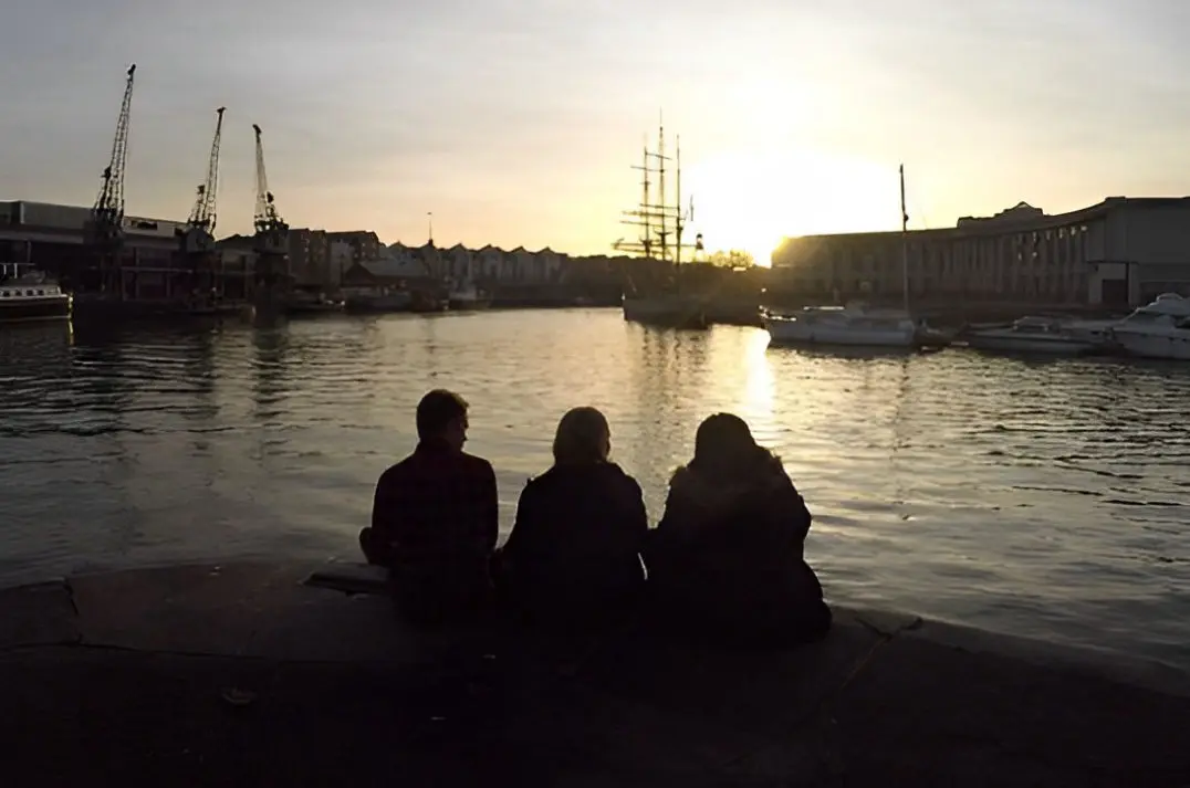 3 people sat overlooking the harbour in Bristol 
